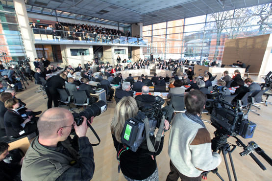 Journalisten in einem Plenarsaal, im Hintergrund findet eine Sitzung statt