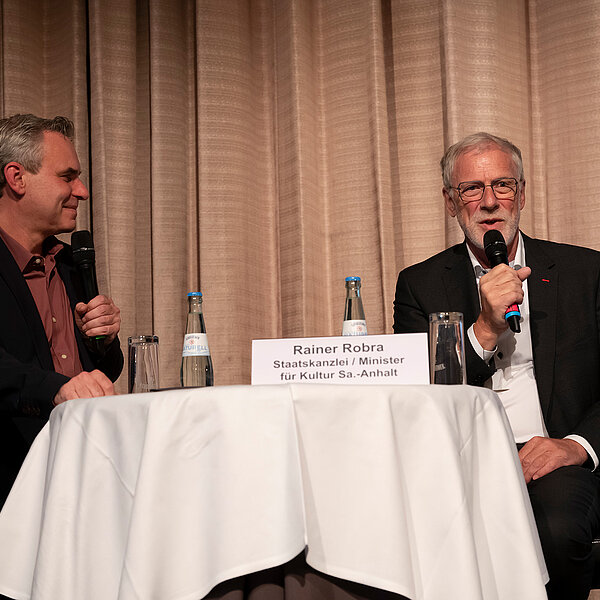 Mit einer medienpolitischen Diskussion wurde am der Verbandstag des Deutschen Journalisten-Verbands in Magdeburg eröffnet. Rainer Robra, Chef der Staatskanzlei Sachsen-Anhalt, stellte sich der Diskussion mit Frank Überall, Bundesvorsitzender des DJV, und den Delegierten. Robra hob die Bedeutung des Journalismus als wichtiger Kraft in Demokratie und Gesellschaft hervor, stellte jedoch einen Zusammenhang zwischen der Höhe des Rundfunkbeitrags und der Akzeptanz des öffentlich-rechtlichen Rundfunks her. Ein höherer Rundfunkbeitrag sei in den Parlamenten der Bundesländer schwer durchsetzbar. DJV-Bundesvorsitzender Frank Überall entgegnete, dass weitere Einsparungen zulasten der Journalistinnen und Journalisten der Sender gingen: „Es gibt keinerlei Rechtfertigung dafür, gute journalistische Arbeit schlechter zu bezahlen.“ Er warf dem Staatskanzleichef „populistisches Vorab-Plattmachen“ einer Beitragserhöhung vor. Die Politik müsse berücksichtigen, dass Medienschaffende so wie alle anderen Menschen auch höhere Stromrechnungen und steigende Mieten zu bezahlen haben. Mehrere Delegierte betonten in der Diskussion mit Robra die schwierige wirtschaftliche Situation der Freien an Rundfunkanstalten.