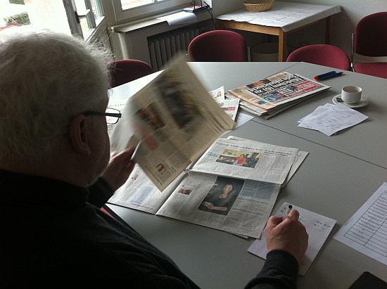 Das Bild zeigt Roland Scheidemann vom DJV-Fachausschuss Bildjournalisten bei der Auswertung von Tageszeitungen, über den Rücken fotografiert. Vor ihm liegen Zeitungen, er hält einen Stift.
