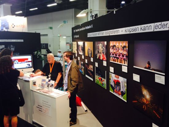 Eine Momentaufnahme des DJV-Stands auf der photokina, zwei Interessenten werden von Thomas Schumann und Frank Schumann (nicht verwandt) beraten. An der Standwand Fotos aus den Fotowettbewerben von DJV-Landesverbänden, sowie die Banderole: Knipsen kann jeder, Bildjournalisten können fotografieren. – Thomas Schumann und Frank Schumann (nicht miteinander verwandt) diskutieren mit einem Berufsveteranen und seiner Begleitung. Foto: Hirschler